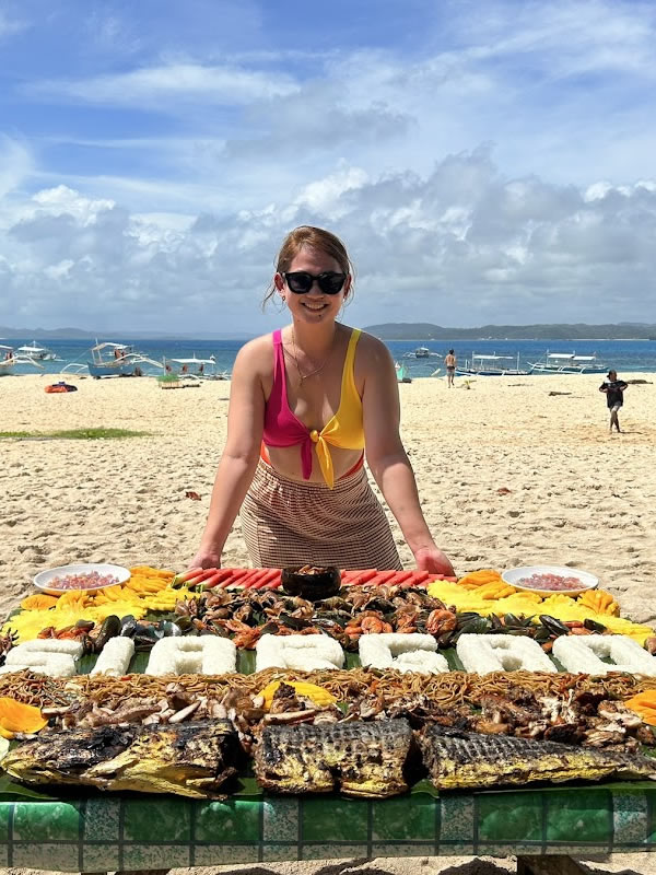 Woman in front of Boodle Fight food in Daku Island Siargao